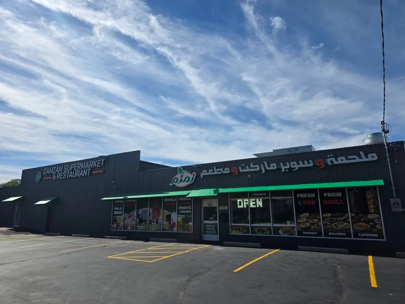 The ZAMZAM storefront on South 13th Street in daylight, with its English and Arabic signs and green awnings.